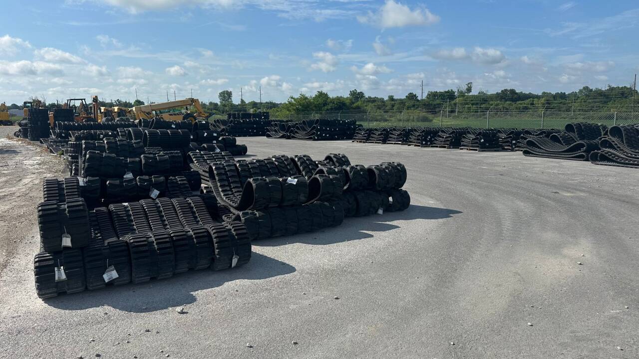 Large inventory of durable rubber tracks and compact equipment undercarriage components stocked at a distributor's outdoor warehouse in North America.